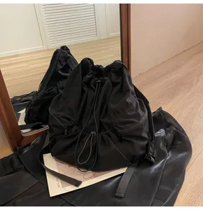 Close-up of black nylon drawstring backpack with pleated texture and adjustable buckle