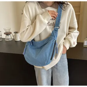 Vue détaillée du sac besace en jean bleu avec large bandoulière et pendentif en corde