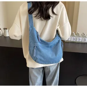 Vue arrière d'un sac bandoulière en denim bleu clair avec pendentif de fermeture tressé