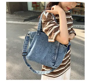 Close-up of washed blue denim fabric texture and adjustable strap on a messenger bag