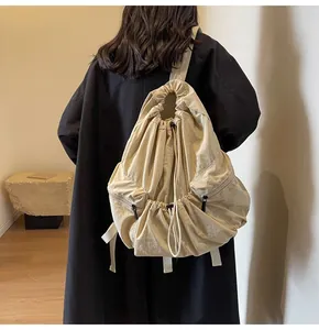 Detailed back view of a beige drawstring nylon backpack on a model in a minimalist room