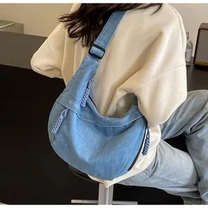 Détail du sac bandoulière en denim bleu clair avec sangle réglable et nœud violet