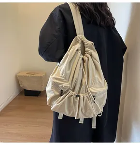 Close-up of beige nylon drawstring backpack showing side zippers and wide shoulder straps