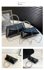 Detail view of black handbag featuring rhinestone ring handle and metal chain strap