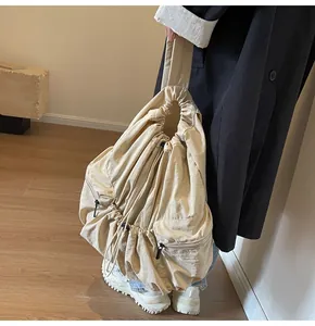 Detail of beige nylon drawstring backpack showing side zipper pockets and pleated texture