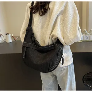 Détail du sac croissant en denim noir avec surpiqûres blanches et zip à nœud tressé