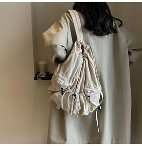 Detail shot of the beige nylon drawstring backpack showing textured fabric and side pockets