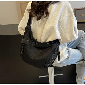 Détail du sac à bandoulière en denim noir avec surpiqûres et tirettes de zip tressées
