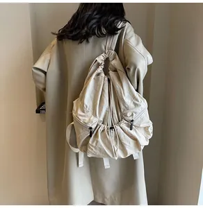 Detail of minimalist beige nylon backpack with drawstring closure and side zipper pocket