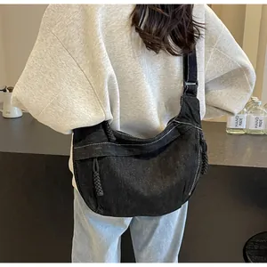 Vue arrière d'un grand sac croissant en denim noir avec surpiqûres sur un mannequin femme