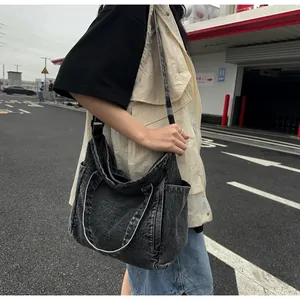 Detail of grey washed denim messenger bag with multi-pockets and adjustable strap