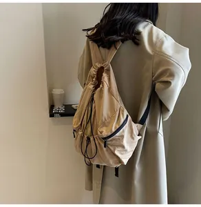Detailed side view of the beige drawstring nylon backpack with a black zipper pocket