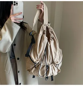 Close-up of beige drawstring nylon backpack with black zipper and functional straps