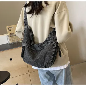 Détails de la grande besace en denim foncé avec tirettes tressées et bandoulière large