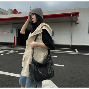 Outdoor shot showing a large washed denim messenger bag with vintage texture and side pocket