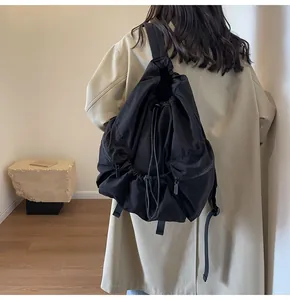 Rear view of a black drawstring nylon backpack being worn for daily commuting