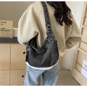 Gros plan du sac bandoulière en denim noir délavé avec large bandoulière réglable