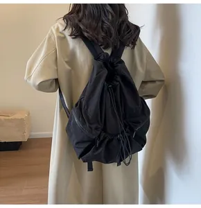 Detail showing the drawstring closure and side zipper pocket of this black nylon backpack