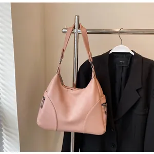 Detail of light pink pebble leather hobo bag with side zippers and round ring strap