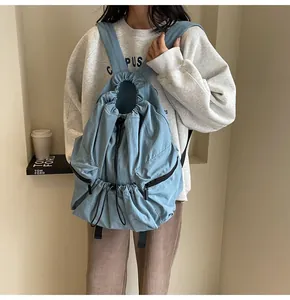 Detail of blue nylon backpack featuring a drawstring closure and dual side zipper pockets