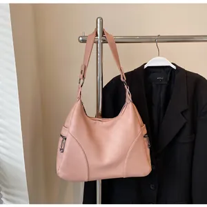Detail of pink pebbled leather shoulder bag with decorative side zippers and metal rings