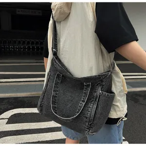 Detail view of large washed denim messenger bag with adjustable strap and side pockets