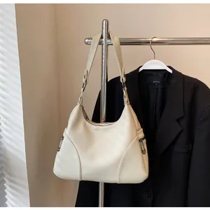 Close-up of cream pebble leather shoulder bag with zipper details and wide strap