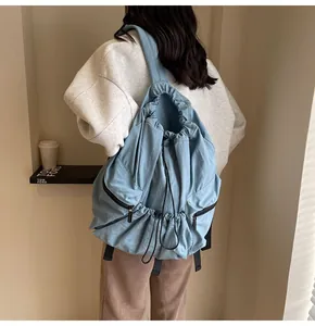 Detail of light blue nylon drawstring backpack featuring side zip pockets and wide straps
