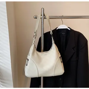 Detail of off-white lychee grain leather hobo bag with side zipper pockets on a rack