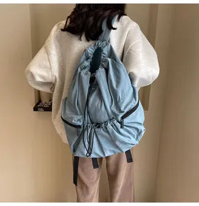 Detail of light blue nylon backpack showing side zipper pocket and drawstring closure