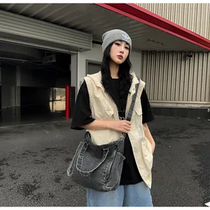 Outdoor street style view of a grey washed denim messenger bag with utility vest