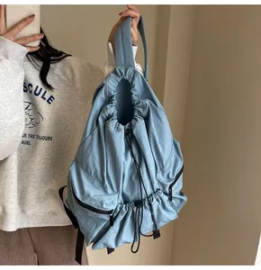 Detail view of light blue nylon backpack showing drawstring closure and side zipper pocket