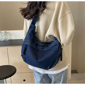 Détail du grand sac besace en denim bleu foncé avec surpiqûres blanches contrastées
