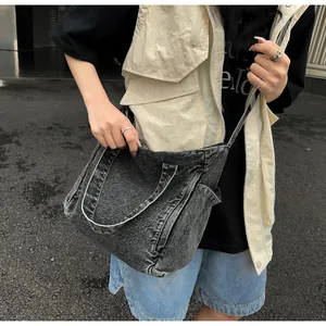 Detail of dark grey washed denim messenger bag featuring side pockets and cross-body strap