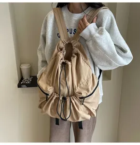 Detailed back view of khaki nylon drawstring backpack with side zippers on model