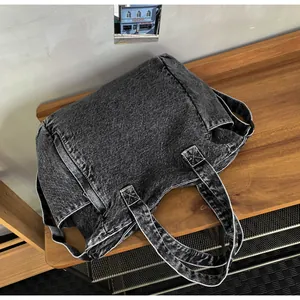 Close-up of washed black denim messenger bag with contrasting white stitching details