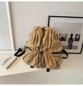 Detail of minimalist khaki nylon backpack with black drawstrings and side zipper pockets