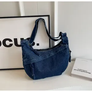 Détails du sac croissant en denim bleu foncé avec fermetures tressées et coutures apparentes