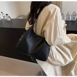 Detail of black leather dumpling bag showing litchi texture and silver side zipper