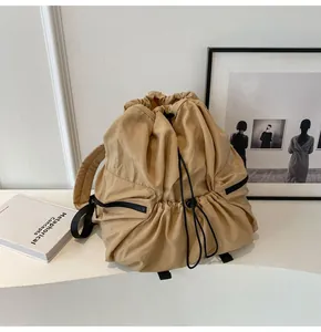 Detail of khaki nylon drawstring backpack with side zippers on a minimalist background