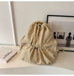 Close-up of beige nylon drawstring backpack with side zipper pocket and webbing straps