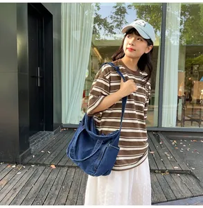 Detailed view of the large capacity dark blue denim messenger bag on model's shoulder