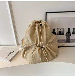 Detail of beige nylon drawstring backpack with side zipper pocket and cloud-like texture