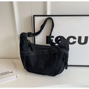 Détail du sac croissant en denim noir avec tissu texturé et tirette en corde tressée