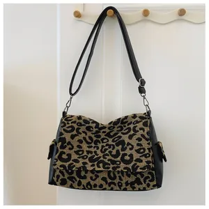 Detail van luipaardprint tote tas met zwarte leren riemen en handig zijvakje op de tas