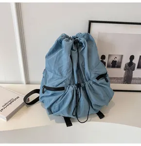 Detail view of light blue nylon backpack showing drawstring closure and front zip pockets
