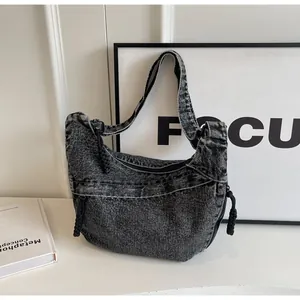 Détail du sac croissant en denim délavé gris foncé avec fermeture éclair tressée
