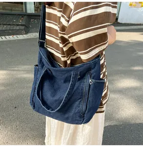 Detail of adjustable strap and washed denim fabric on large messenger bag for men and women
