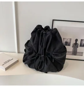 Detail view of the black drawstring nylon backpack with textured fabric and side pockets