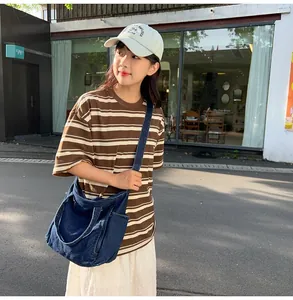 Outdoor shot of a navy blue denim messenger bag showing high capacity and casual style